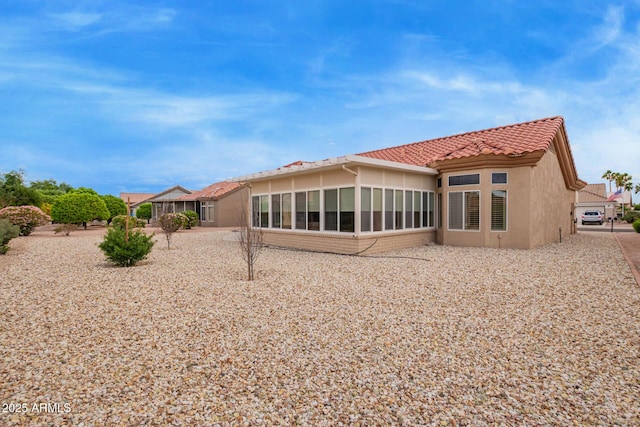 rear view of house with a tiled roof and stucco siding