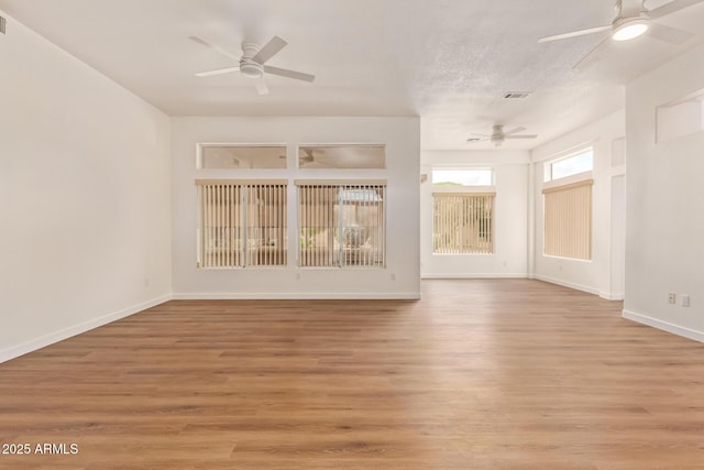 spare room with light wood-style floors, baseboards, a ceiling fan, and visible vents