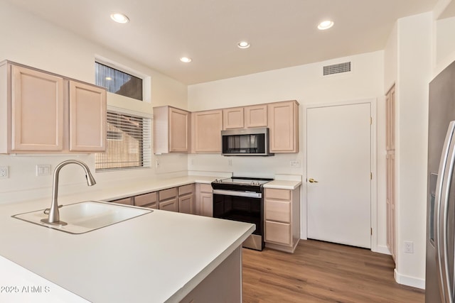 kitchen with visible vents, light brown cabinetry, light countertops, a sink, and appliances with stainless steel finishes
