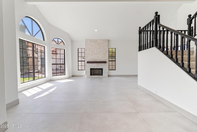 3520 N 110th Ave, Avondale, AZ 85392 - unfurnished living room with baseboards, high vaulted ceiling, a large fireplace, and a healthy amount of sunlight