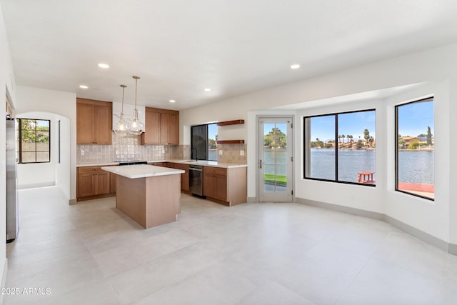 3520 N 110th Ave, Avondale, AZ 85392 - kitchen with light countertops, stainless steel appliances, decorative backsplash, a kitchen island, and brown cabinetry