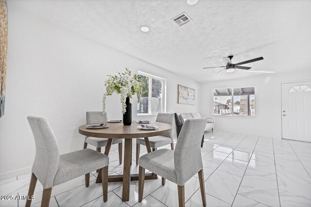 dining area with ceiling fan, visible vents, marble finish floor, and a textured ceiling