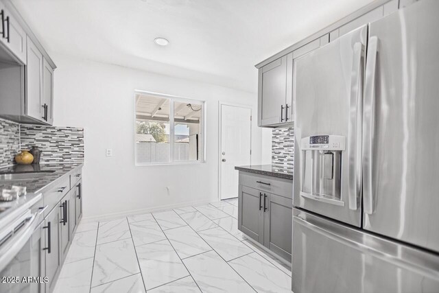 kitchen featuring dark stone countertops, marble finish floor, stainless steel fridge with ice dispenser, and gray cabinetry