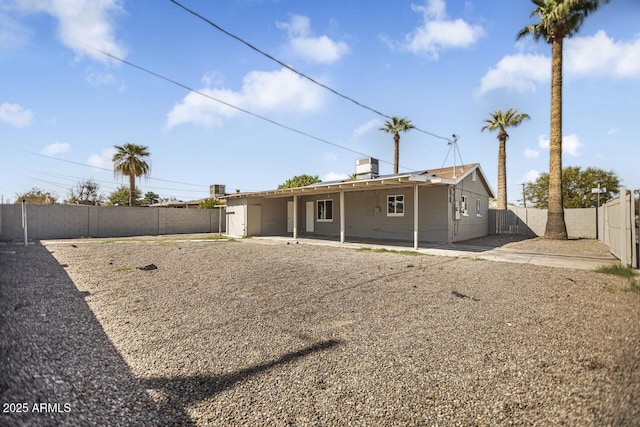 rear view of property featuring a fenced backyard and a patio