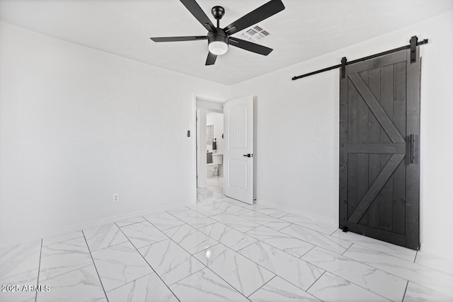 spare room featuring visible vents, baseboards, ceiling fan, a barn door, and marble finish floor