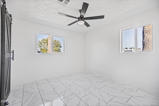 unfurnished bedroom with visible vents, marble finish floor, a ceiling fan, and a barn door