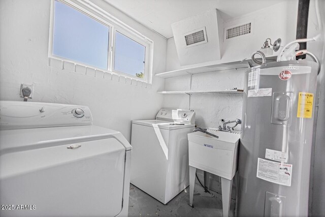 clothes washing area with laundry area, visible vents, water heater, and washer and clothes dryer