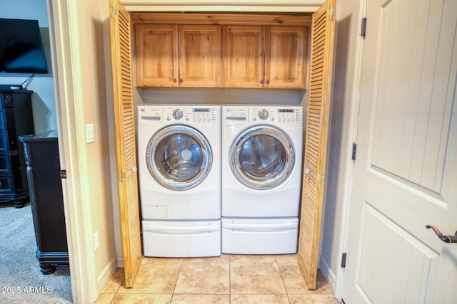 laundry area featuring separate washer and dryer, light tile patterned floors, and cabinets