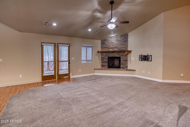 unfurnished living room with ceiling fan, a stone fireplace, lofted ceiling, and light wood-type flooring