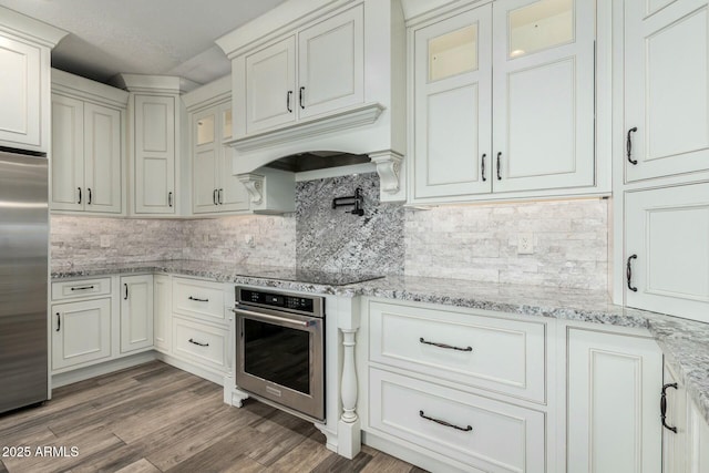 1051 E Julie Ave, San Tan Valley, AZ 85140 - kitchen featuring glass insert cabinets, light wood-style flooring, tasteful backsplash, appliances with stainless steel finishes, and custom range hood