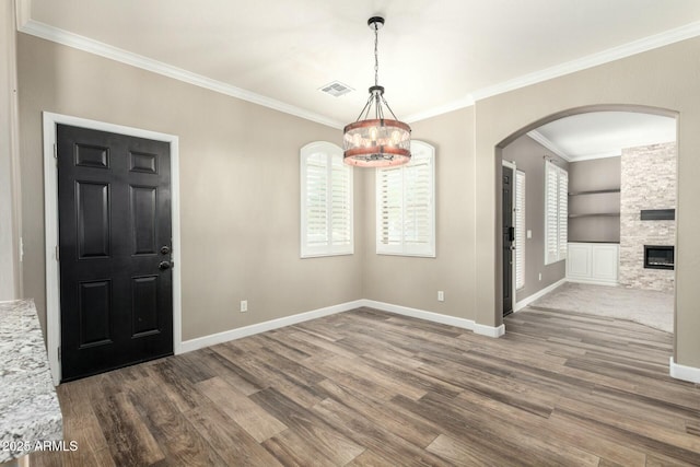1051 E Julie Ave, San Tan Valley, AZ 85140 - unfurnished dining area featuring a notable chandelier, baseboards, visible vents, arched walkways, and wood finished floors