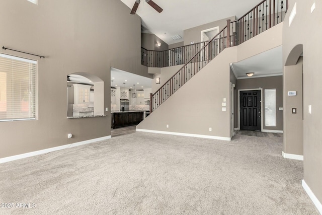 1051 E Julie Ave, San Tan Valley, AZ 85140 - unfurnished living room with ceiling fan, carpet, arched walkways, a high ceiling, and baseboards