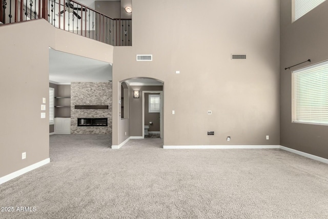 1051 E Julie Ave, San Tan Valley, AZ 85140 - unfurnished living room with arched walkways, baseboards, carpet, and visible vents
