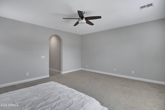 unfurnished bedroom featuring arched walkways, carpet, visible vents, and baseboards