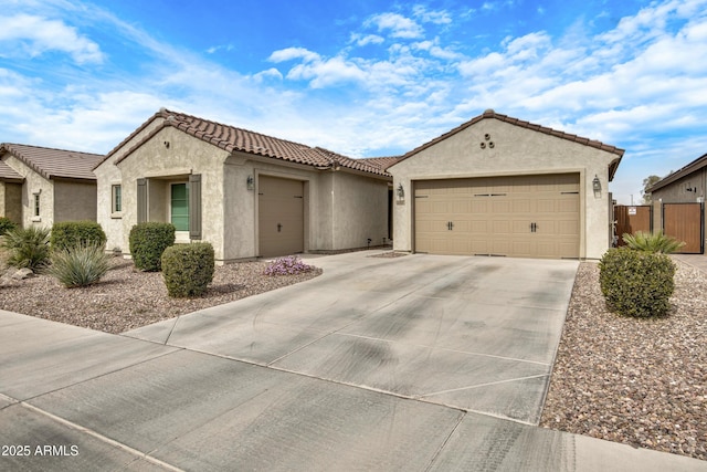 mediterranean / spanish house with an attached garage, fence, a tile roof, concrete driveway, and stucco siding