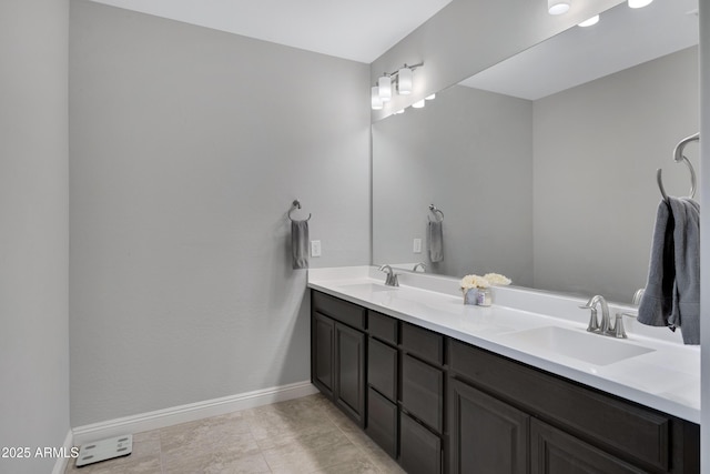 bathroom with a sink, baseboards, and double vanity