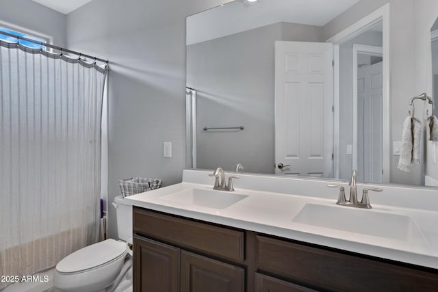 full bathroom featuring a sink, toilet, and double vanity