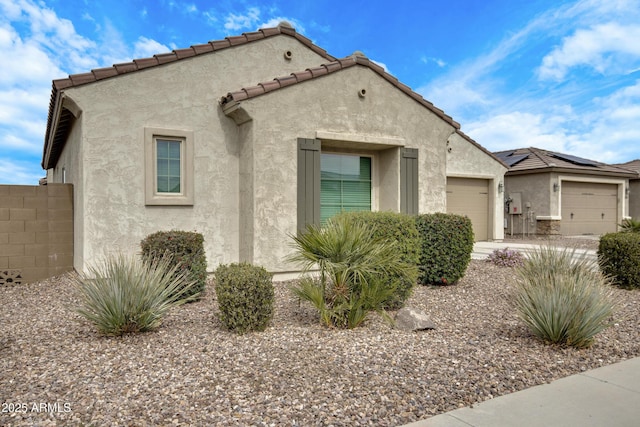 view of front of home featuring a tiled roof, an attached garage, and stucco siding