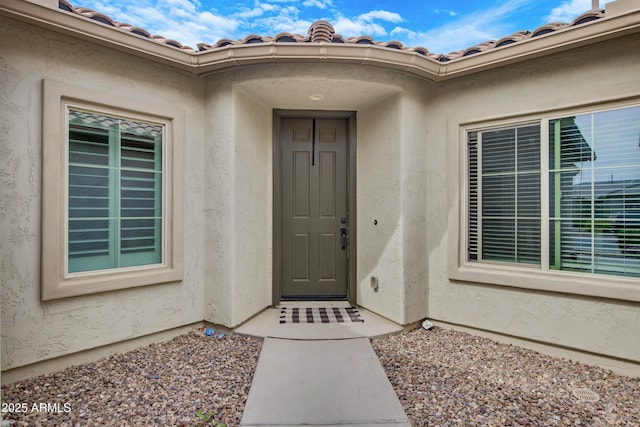 property entrance featuring a tiled roof and stucco siding