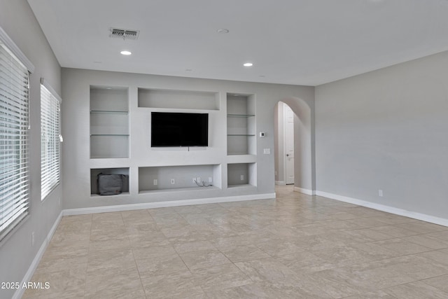 unfurnished living room with baseboards, visible vents, arched walkways, built in shelves, and recessed lighting