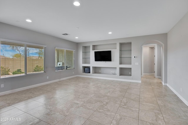 unfurnished living room featuring built in features, arched walkways, recessed lighting, visible vents, and baseboards