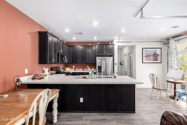 kitchen with kitchen peninsula, light wood-type flooring, and stainless steel appliances