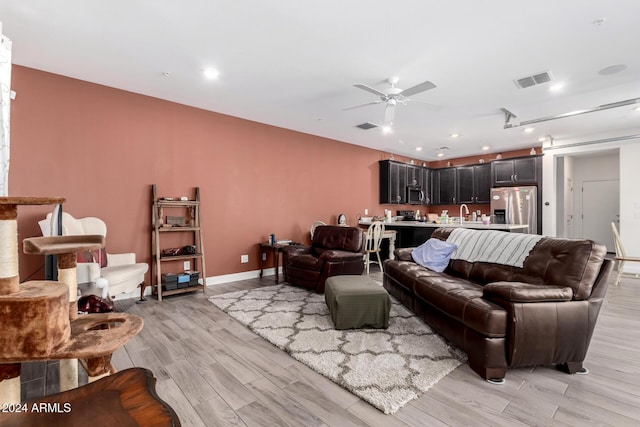 living room featuring ceiling fan, sink, and light hardwood / wood-style flooring