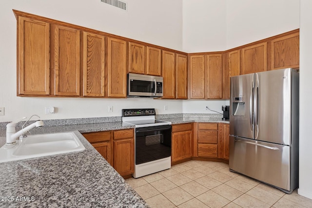 4701 W Fallen Leaf Ln, Glendale, AZ 85310 - kitchen featuring appliances with stainless steel finishes, light tile patterned floors, and brown cabinetry