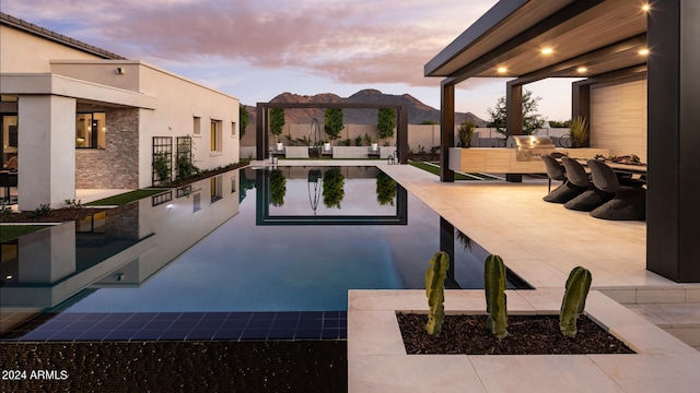 pool at dusk with a patio area and an outdoor living space