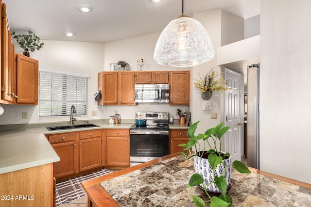 kitchen with decorative light fixtures, vaulted ceiling, appliances with stainless steel finishes, and sink