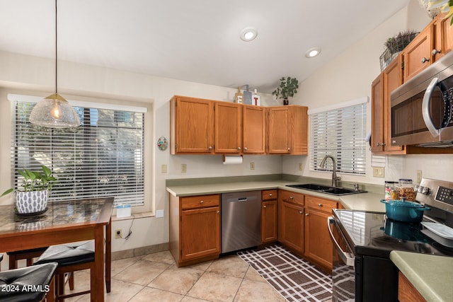 kitchen with hanging light fixtures, vaulted ceiling, light tile patterned floors, stainless steel appliances, and sink