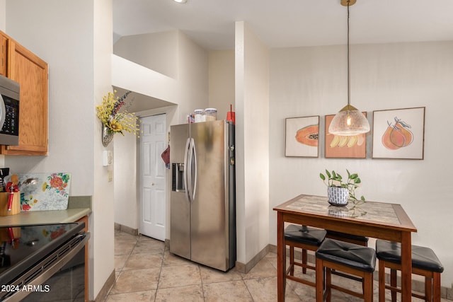 kitchen with pendant lighting, appliances with stainless steel finishes, and light tile patterned floors