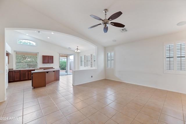 unfurnished living room with vaulted ceiling, light tile patterned floors, and ceiling fan with notable chandelier