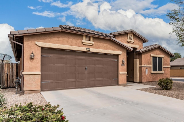 view of front of house with an attached garage, driveway, a tiled roof, and stucco siding