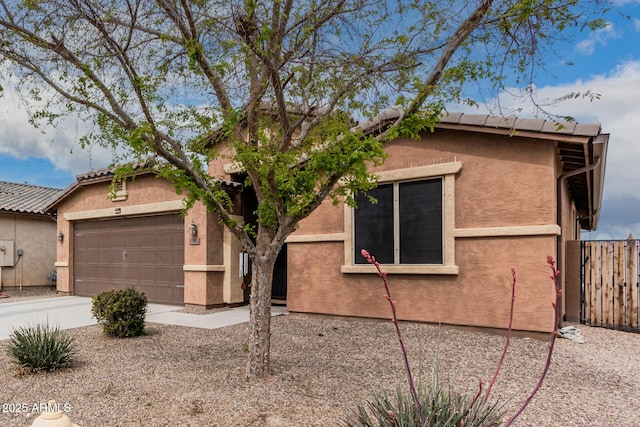 view of front of home featuring concrete driveway, fence, an attached garage, and stucco siding