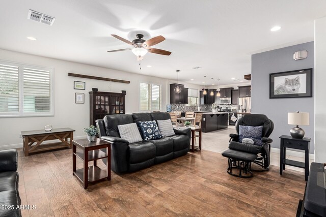 living room with baseboards, visible vents, wood finished floors, and recessed lighting