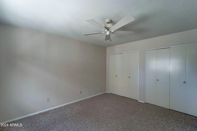 unfurnished bedroom with carpet floors, ceiling fan, and multiple closets