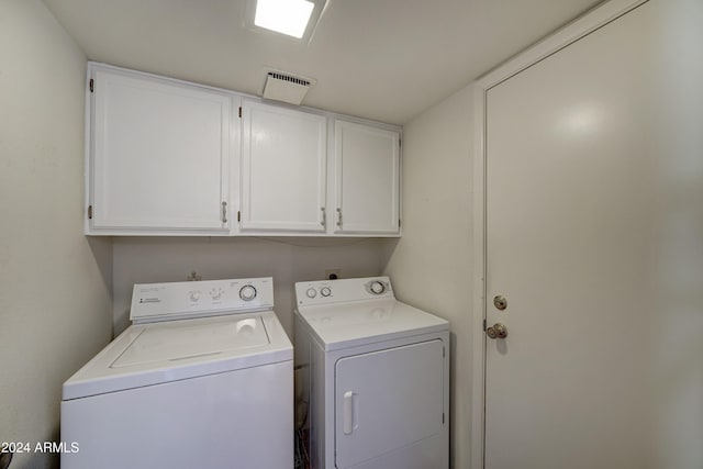 clothes washing area with washing machine and clothes dryer and cabinets