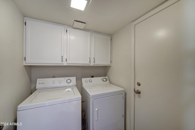 clothes washing area with cabinets and washing machine and clothes dryer