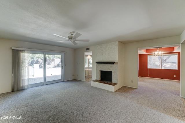 unfurnished living room featuring ceiling fan with notable chandelier, carpet floors, and a fireplace