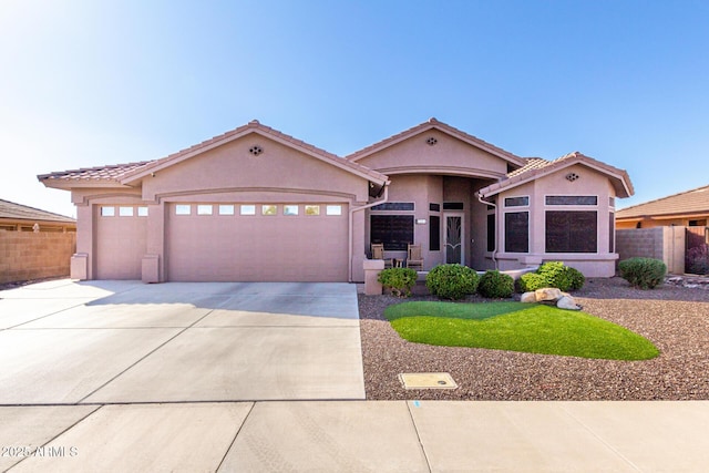 mediterranean / spanish house featuring driveway, a tiled roof, an attached garage, fence, and stucco siding