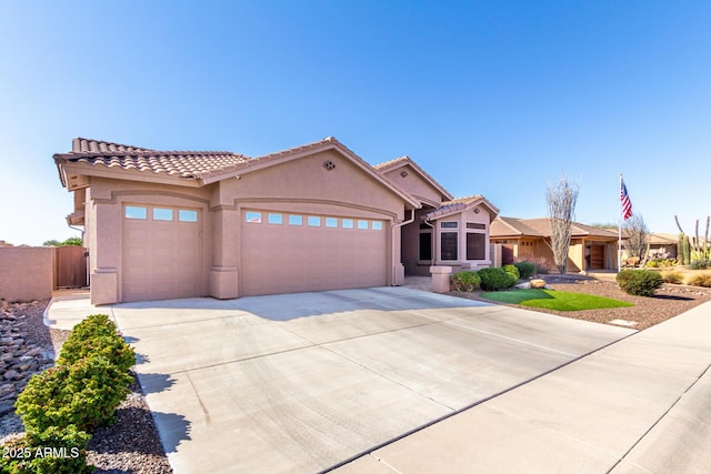 view of front facade featuring stucco siding, an attached garage, fence, driveway, and a tiled roof