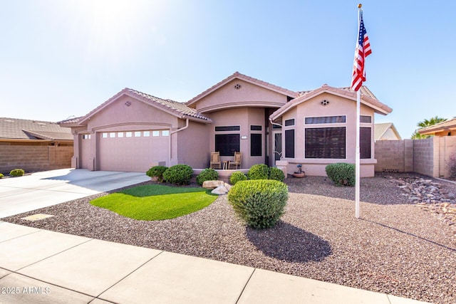 view of front of house with a tile roof, stucco siding, an attached garage, fence, and driveway