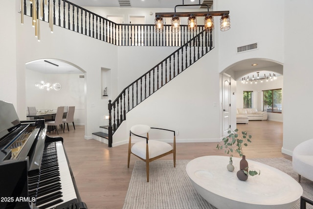 4960 E Colonial Dr, Chandler, AZ 85249 - entryway featuring arched walkways, a chandelier, wood finished floors, a towering ceiling, and stairs
