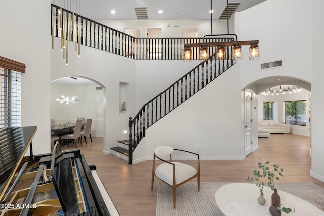 4960 E Colonial Dr, Chandler, AZ 85249 - entrance foyer featuring arched walkways, wood finished floors, a chandelier, stairway, and a high ceiling