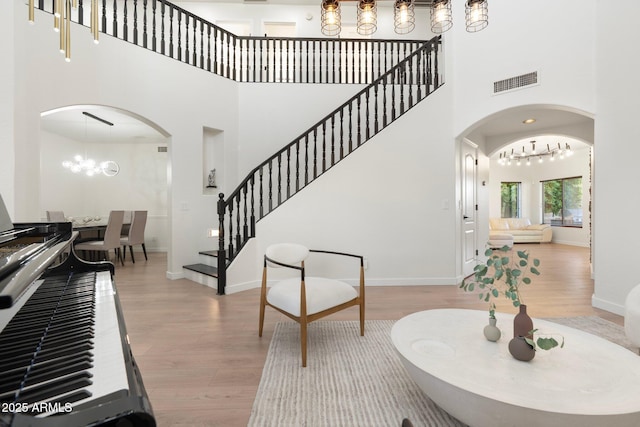 4960 E Colonial Dr, Chandler, AZ 85249 - foyer entrance featuring arched walkways, a chandelier, wood finished floors, a high ceiling, and stairway