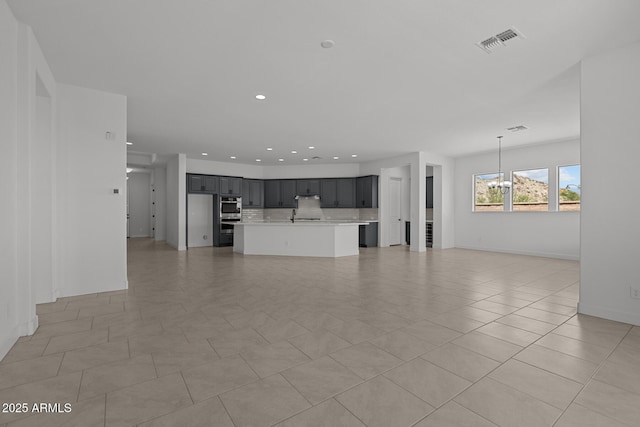 21541 W Mariposa St, Buckeye, AZ 85396 - unfurnished living room with a chandelier, recessed lighting, a sink, light tile patterned flooring, and baseboards