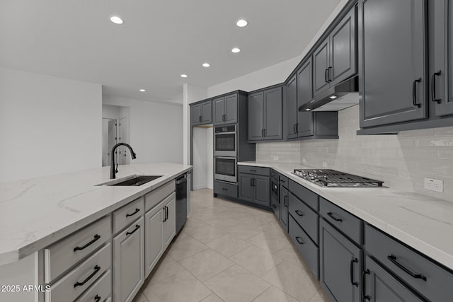 21541 W Mariposa St, Buckeye, AZ 85396 - kitchen featuring a sink, appliances with stainless steel finishes, under cabinet range hood, backsplash, and light stone countertops