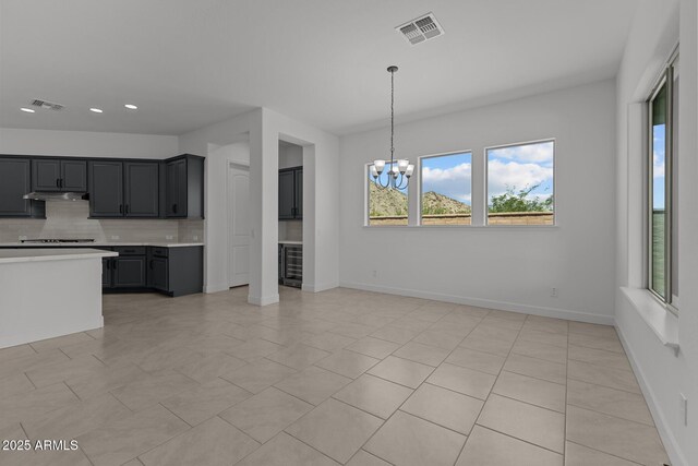 21541 W Mariposa St, Buckeye, AZ 85396 - kitchen with tasteful backsplash, a chandelier, light countertops, beverage cooler, and cooktop
