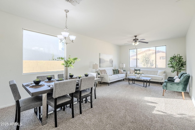 carpeted dining room featuring visible vents and ceiling fan with notable chandelier